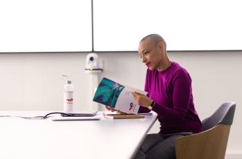 Employee alone in a meeting room in front of her laptop with note sheets and water bottle